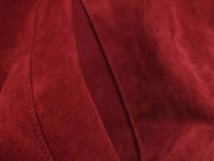 Close-up of red suede fabric texture and reinforced stitching on a jacket pocket