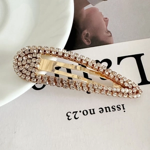 Detailed close-up of a teardrop-shaped hair clip with shimmering pavé rhinestones
