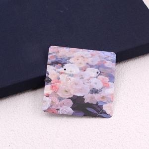 Macro detail of square floral earring display card with pink and white rose patterns