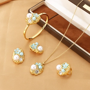 Luxurious gold jewelry set with blue floral motifs and pearls on a satin surface
