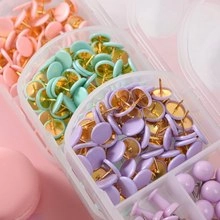 Close-up of pastel pink, mint green and purple thumbtacks in a clear storage box