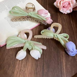 Detailed close-up of tulip ribbon hair claws in pink, white, and purple on a vintage book