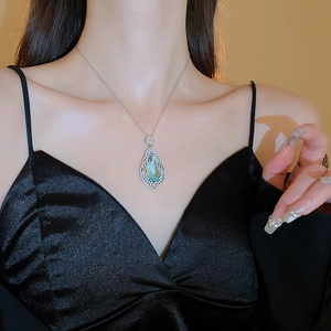 Close-up of teardrop-shaped light blue pendant necklace with micro-pave crystals on model