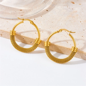 Golden round hoop earrings with textured metal mesh design on light stone background
