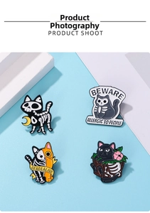 Detail of four enamel skeleton cat pins featuring spooky designs and cat slogans