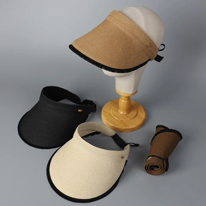 Detail of foldable straw sun visor with fringed edges and metal bee accent for women