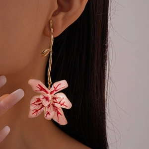 Detail of pink floral drop earring with gold branch design on a female model