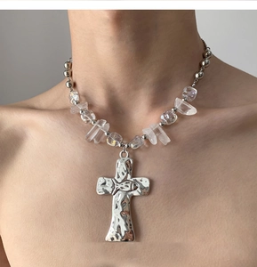 Detail of cross pendant with hammered texture and crystal beads on a statement necklace
