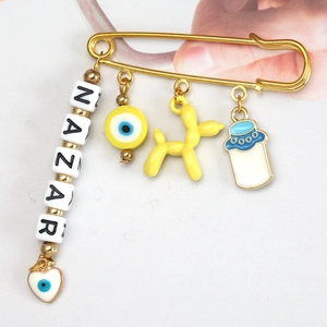 Detailed close-up of golden brooch with NAZAR letter beads and colorful lucky charms