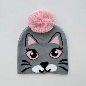 Close-up of kids knitted beanie with pink pompom and gray cat jacquard pattern detail