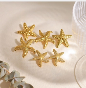 Détail de trois paires de boucles d'oreilles étoiles de mer dorées avec texture en relief
