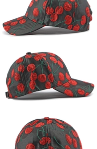Close-up detail of embroidered red cherry patterns on a black satin baseball cap