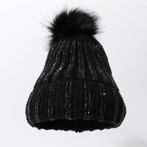 Detail of black ribbed knit beanie featuring sparkling rhinestones and a fluffy faux fur pom
