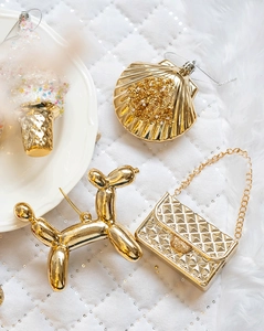 Macro shot of gold ornaments including balloon dog and seashell on white quilted fabric