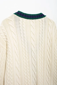 Close-up of cable knit sweater with green and blue striped ribbed neckline detail