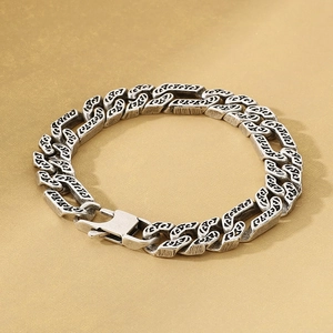 Macro view of vintage silver NK chain links with detailed scrollwork floral engraving