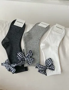 Detailed view of combed cotton mid-calf socks with plaid bow tie accents in grey and white