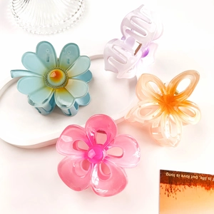Detail of four colorful hollow plumeria hair claws in blue, pink, orange, and purple resin