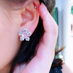Close-up of sparkling five-petal cherry blossom stud earrings with pink and white gems