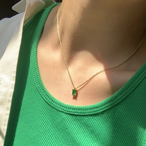Detail of 18K gold plated necklace with rectangular emerald zircon pendant on model