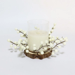 Gros plan d'une bougie blanche en verre avec base en bois et couronne de baies blanches