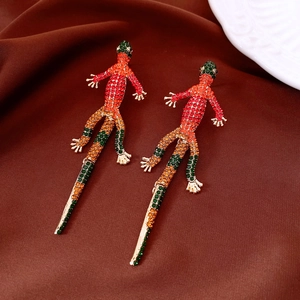 Dettaglio di orecchini a lucertola vintage con strass colorati su tessuto marrone