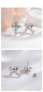 Macro detail of silver cross stud earring with light blue gemstone and screw back closure