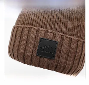 Close-up of brown knit winter hat featuring vertical stripes and a leather mountain patch