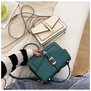 Detail view of stylish square handbags in off-white and dark green with gold metal buckles
