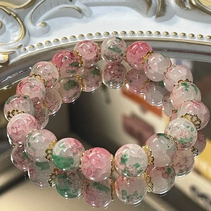 Pink and green gradient glass bead bracelet with gold spacers on reflective mirror base