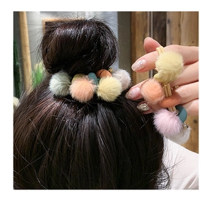 Dettaglio di elastico in peluche con perline colorate su acconciatura a chignon e mano