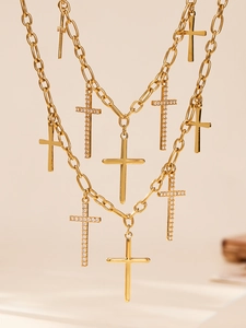 Détail d'un collier doré multicouche avec pendentifs croix polis et sertis de zircons