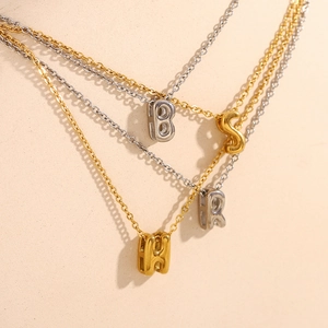 Gros plan de pendentifs lettres évidées en or et argent sur des supports bijoux