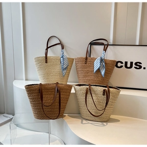 Detail of straw tote bags with silk scarves and brown leather handles in vacation style