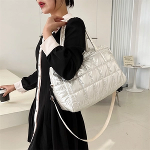 Silver quilted puffer tote bag with dual handles and crossbody strap in a modern setting