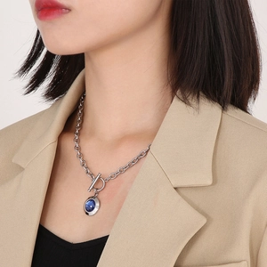 Detail of silver OT buckle chain necklace with a blue round crystal pendant on model