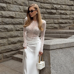 Top ajustado de encaje blanco con manga larga y falda larga de satén para un look chic