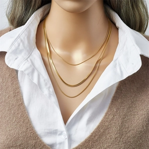 Detailed close-up of a triple layered gold herringbone snake chain necklace on a model