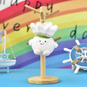 Detailed view of soft cartoon shuttlecock plush toy keychain with smiling face and gold hook.