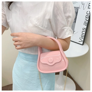 Mini macaron pink jelly bag with gold chain shown held by a model in a cozy setting