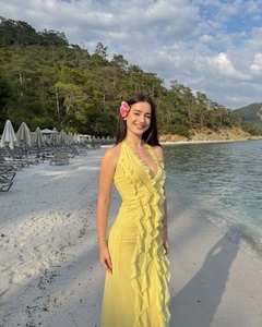Close-up of bright yellow ruffled maxi dress with deep V-neck in a sunny beach setting