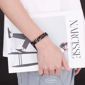 Detail of gunmetal stainless steel cuban chain bracelet on male wrist with magazine