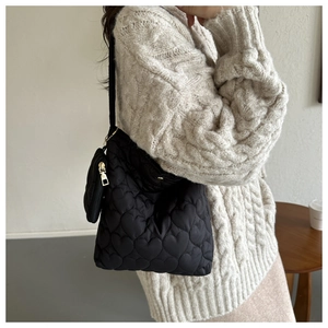 Detail of black quilted tote bag with heart pattern and a small round coin purse