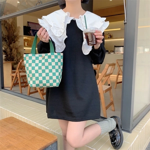 Detail of a vintage green and white checkerboard corduroy tote bag held by a model