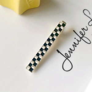 Detail of checkered hair clip featuring inlaid pearls and sparkling rhinestones on metal