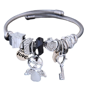 Pulsera plateada con dijes de cisne, llave de corazón y estrella en banda de cable de acero