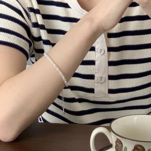 Detailed view of a minimalist silver chain bracelet on a wrist with adjustable clasp