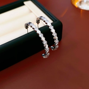 Boucles d'oreilles créoles hexagonales en argent avec zircons dans un écrin noir