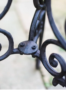 Détail d'un support de plante en fonte noire montrant les volutes et l'assemblage robuste