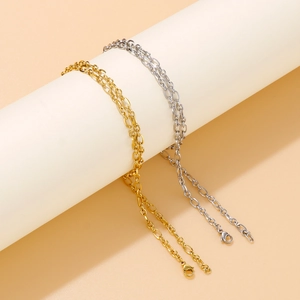 Minimalist gold and silver O-link chains displayed elegantly on a cylindrical pedestal